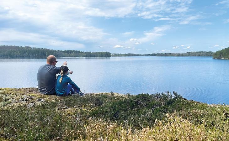 Pappa och dotter tittar ut över sjö och pekar mot vattnet.