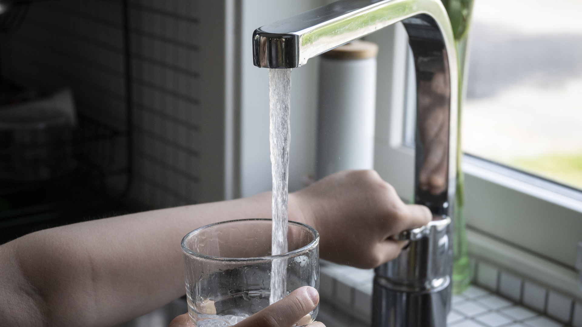 Vattenkran fyller glas med vatten