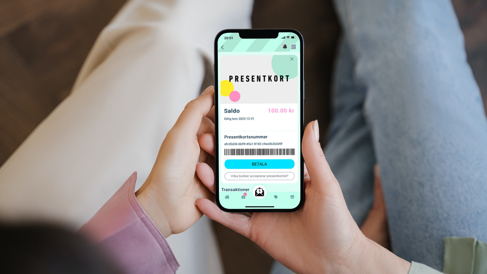 Två händer håller i mobil med webbplats för köp av presentkort.