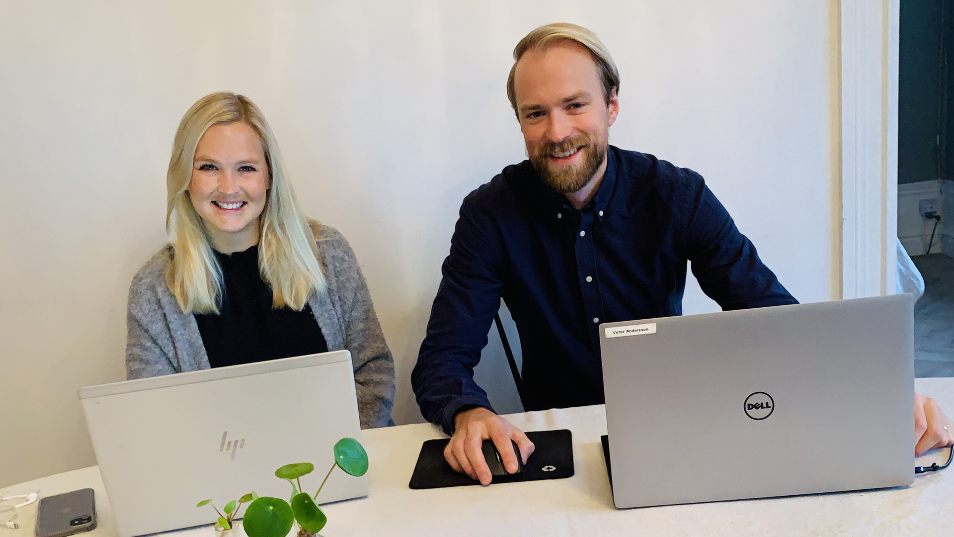 Victor och Linnea sitter med sina laptops vid köksbordet och jobbar hemifrån.