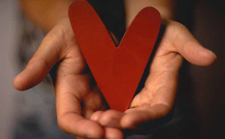 två händer som håller i ett rött hjärta