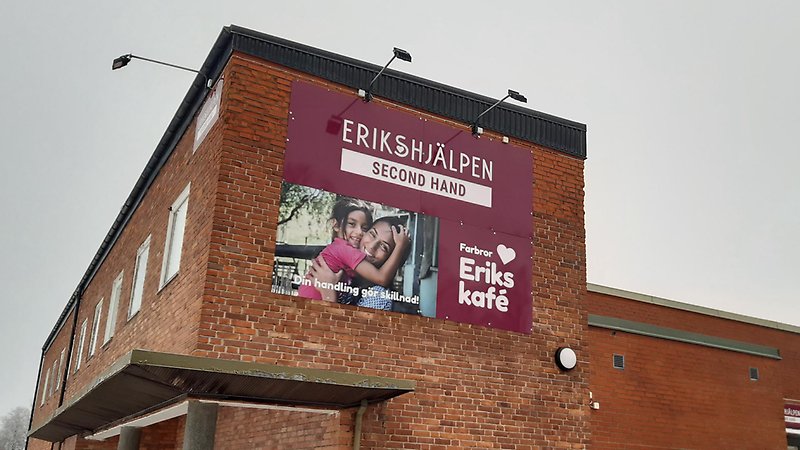 Brun tegelbyggnad med fasadskylt Erikshjälpen Second Hand.