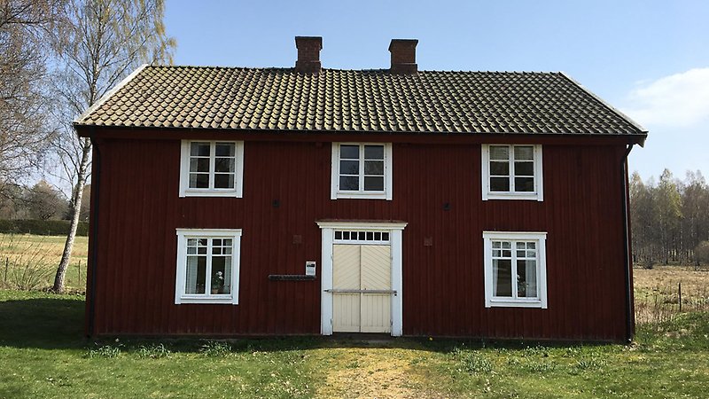 Röd byggnad med fönster och en gul dörr