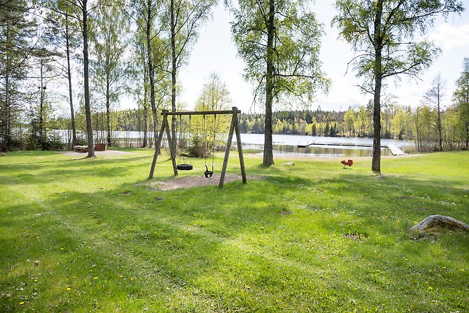 Stor gräsyta, gungor, sjö med bryggor.