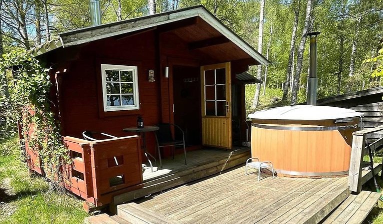 Röd bastu med trädäck och badtunna