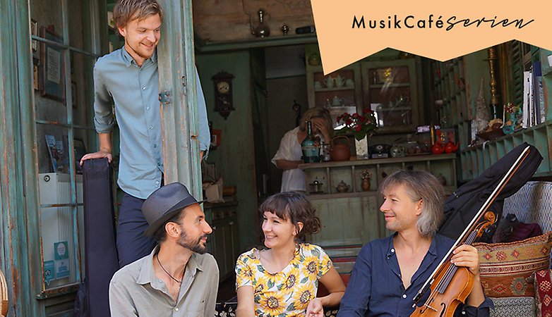 Tre män och en kvinna sitter utanför ett café.